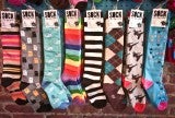 A row of long socks with different patterns and colors, such as a black-and-white striped pair of socks and a rainbow pair.