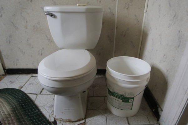The toilet in Aaron Barkley and Gloria Irizarry’s home and the bucket of water that is used to flush.