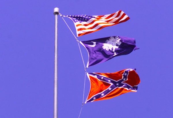 FILE PHOTO 6APR00 - The American flag and South Carolina state flag fly above the confederate flag at the statehouse in Columbia, South Carolina, in this April 6 file photo. The confederate flag will come down on Saturday, and a new flag is said to be going up at a Confederate monument on the Statehouse grounds. Flag opponents insist they'll continue to boycott the state until no Congederate flag flies on the Statehouse grounds. TLC/SV/MMR - RTR5UC9