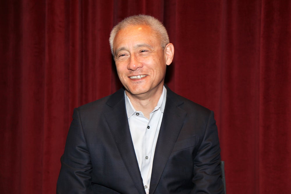 John Matsusaka in a black suit staring slightly to the left with a smile.