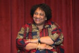 Shirley Weber in a patterned shirt looking slightly to the left with a smile and with arms almost crossed.